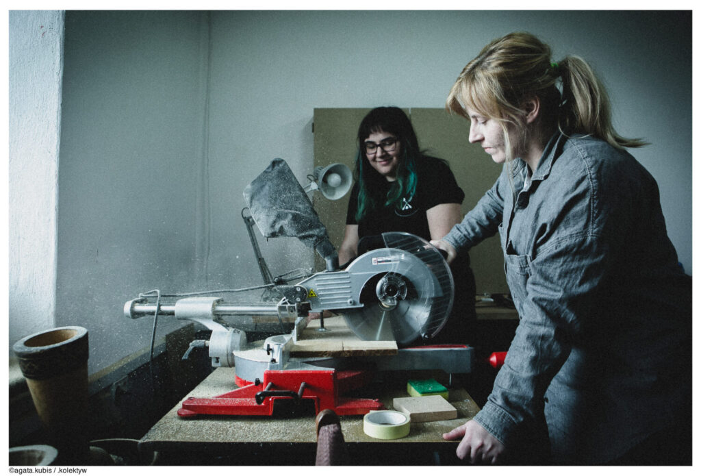 Dwie dziewczyny pracują w warsztacie, na stole różne materiały, narzędzia i sprzęty