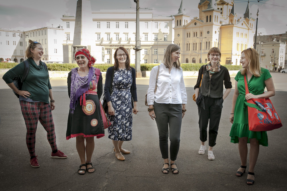 6 kobiet stojących w rzędzie na tle miejskiego placu