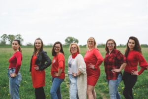 grupa kobiet w rzędzie ubrana na czerwono na tle łąki